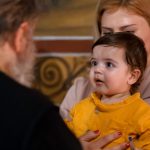 A touching family moment during an indoor church event, showing a child held by a parent.