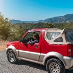 A red SUV driving through the mountainous landscape of Alanya, Turkey on a sunny day.