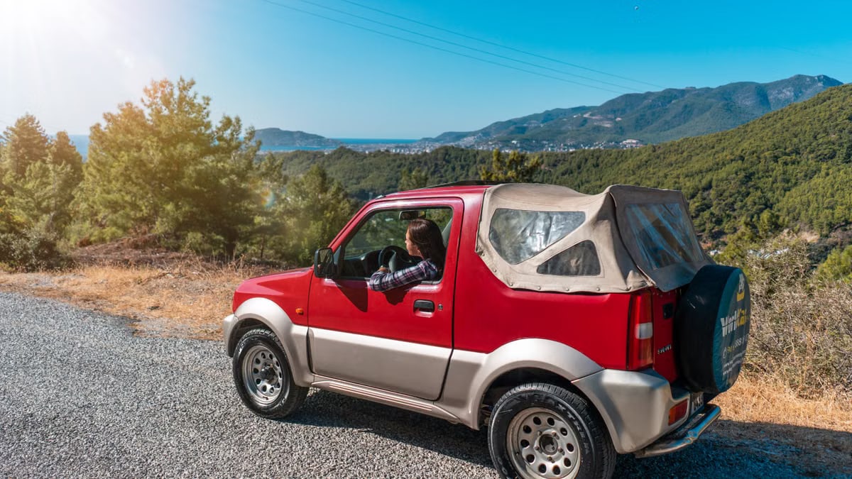 A red SUV driving through the mountainous landscape of Alanya, Turkey on a sunny day.